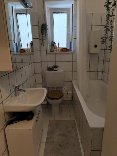 Kleines Badezimmer mit WC, Waschbecken und Badewanne, gefliest und hell.