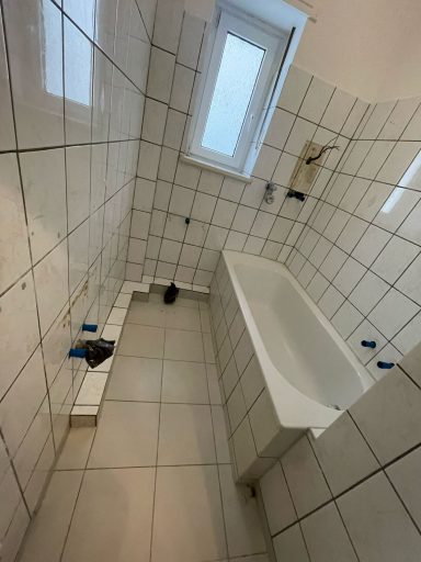 Badezimmer mit Wanne, Fliesen und Fenster, unvollständig installiert.